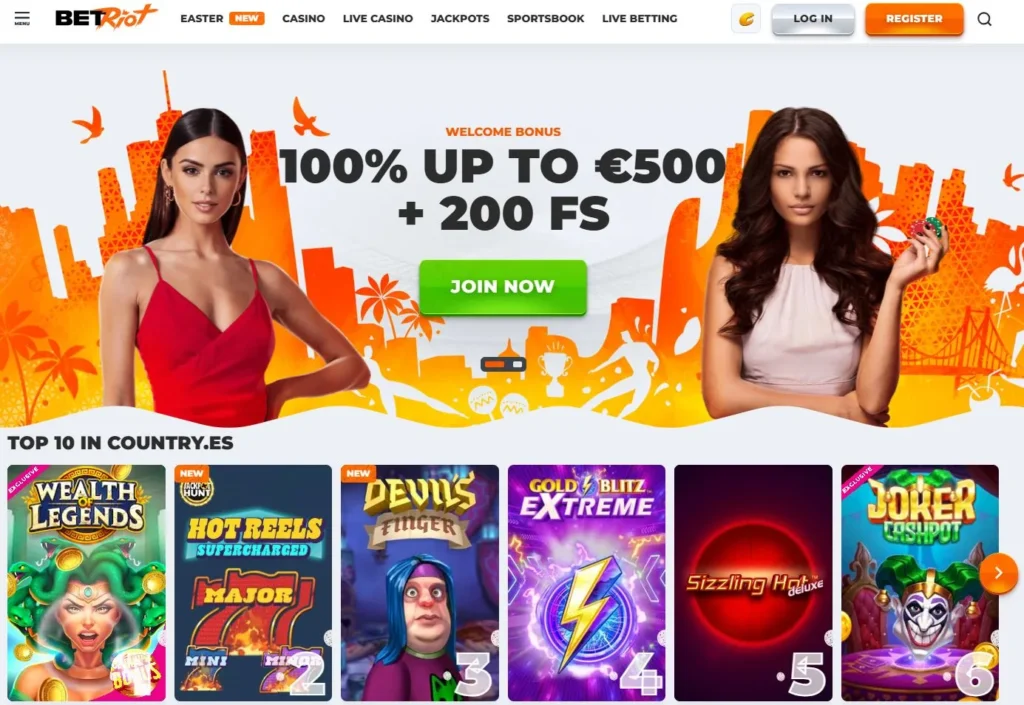 Banner de BetRiot con bono de bienvenida del 100% hasta 500 € más 200 giros gratis, acompañado de dos modelos y fondo naranja con ilustraciones de ciudad. Debajo se muestra el Top 10 de juegos en España, incluyendo Wealth of Legends, Hot Reels Supercharged, Devil's Finger, Gold Blitz Extreme, Sizzling Hot Deluxe y Joker Cashpot.